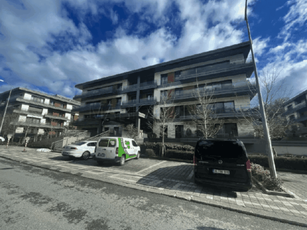 geniş ve çok katlı olmayan site ve önüne park etmiş araçlar