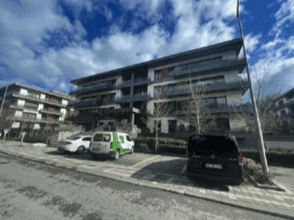 geniş ve çok katlı olmayan site ve önüne park etmiş araçlar